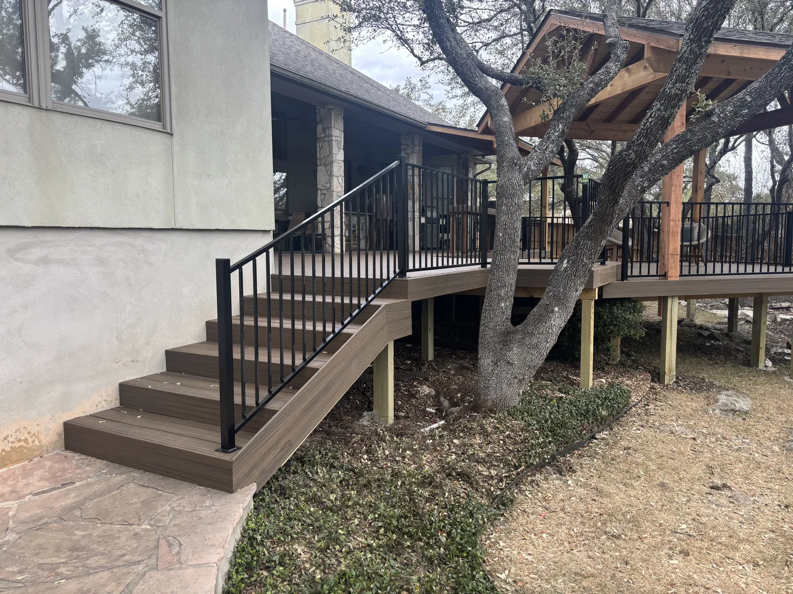 Composite deck stairs with a black handrail leading up to a raised deck