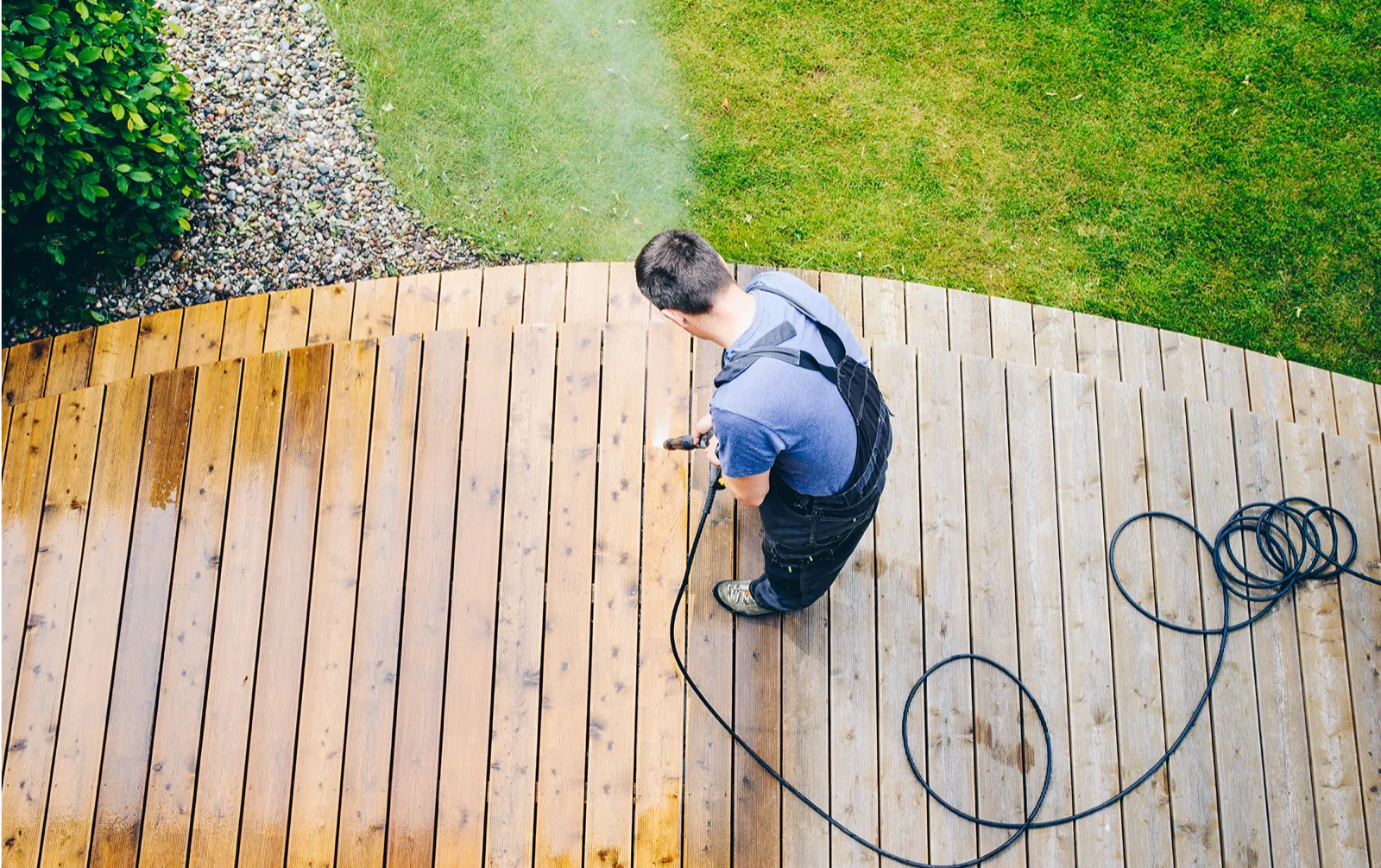 Overhead view of a wood deck being pressure washed, boards half clean