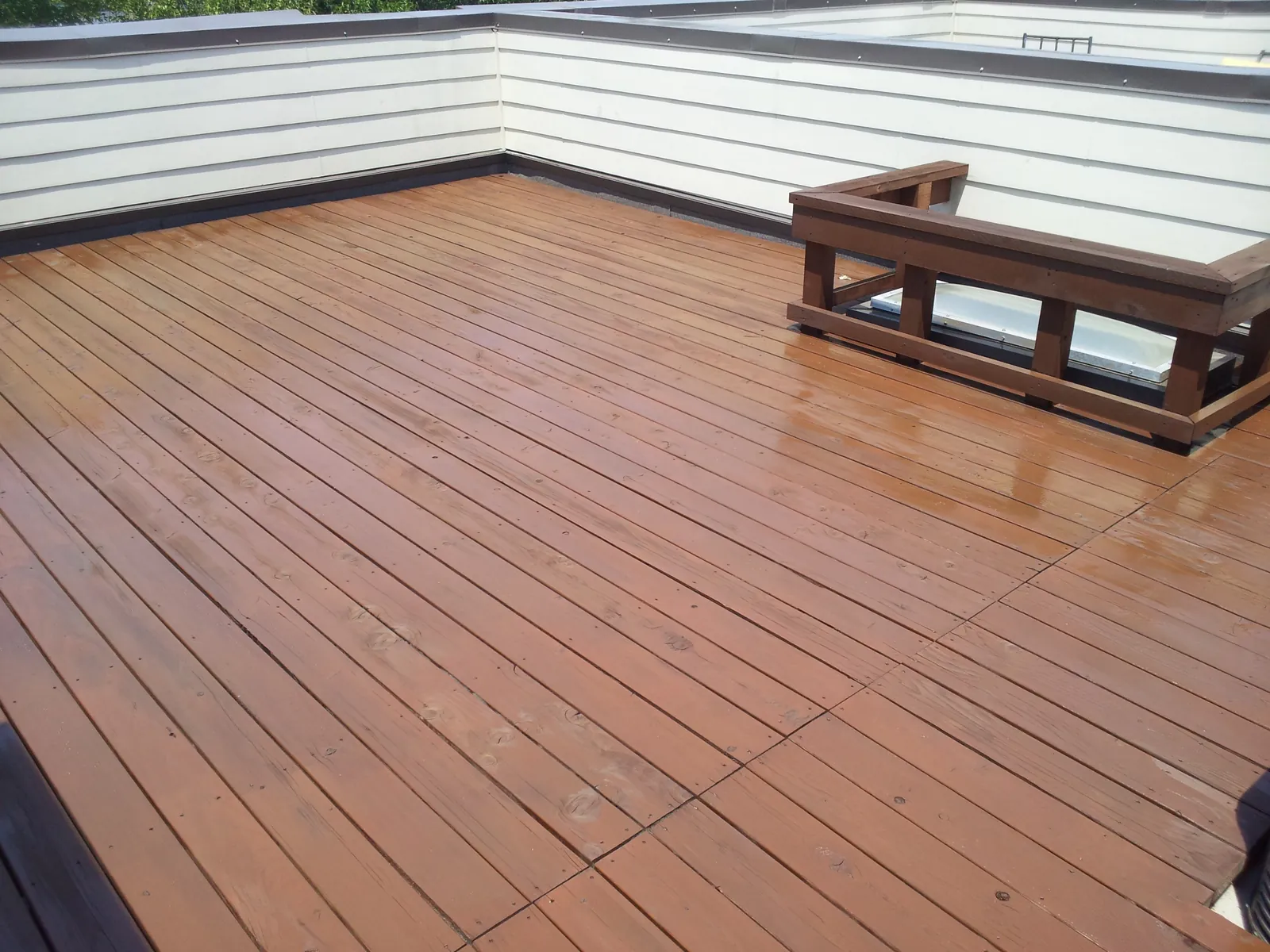 Wood deck with a fresh brown deck stain and a built-in bench along one side