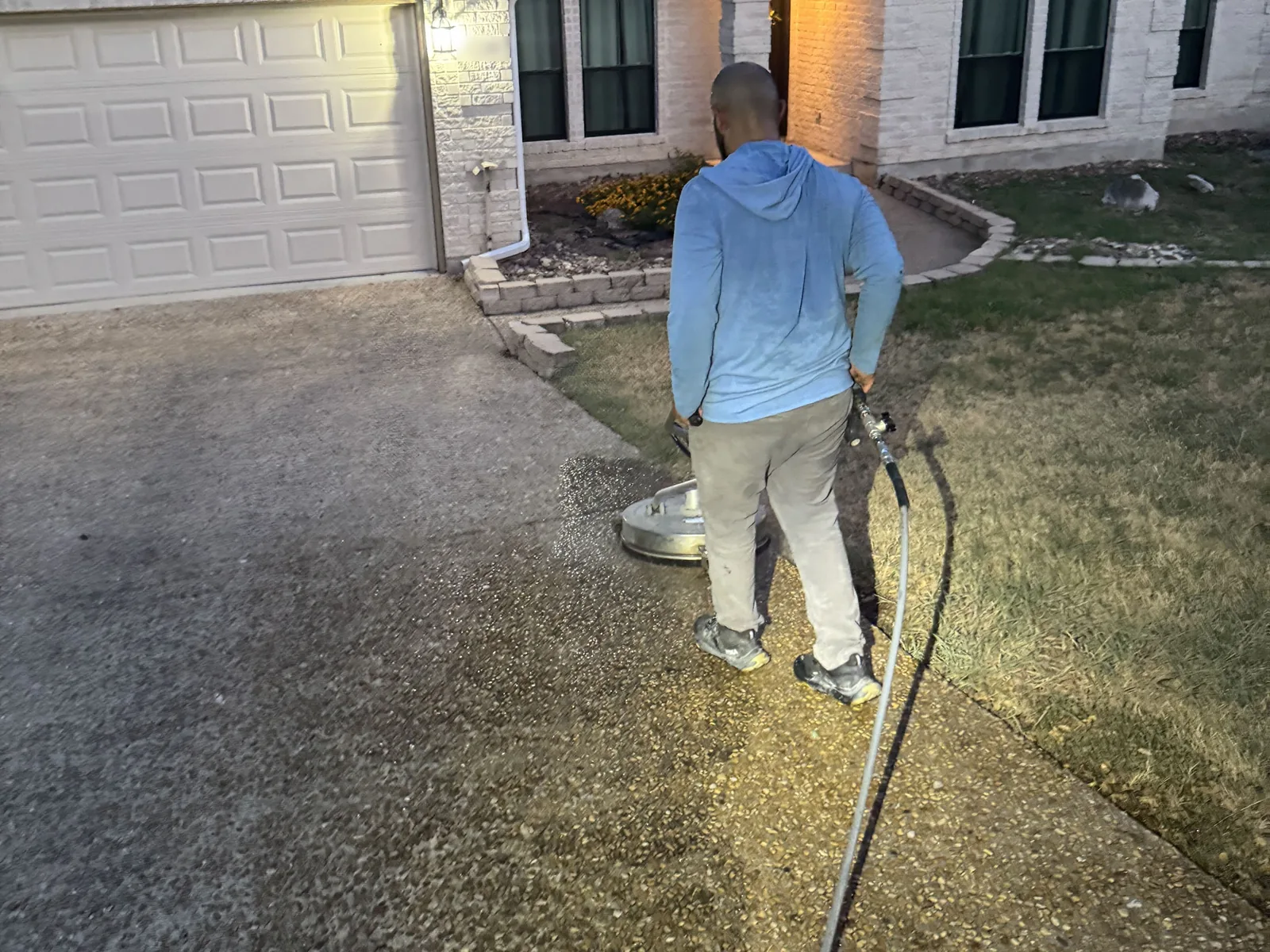 Surface cleaner washing a concrete driveway at a home, evening job