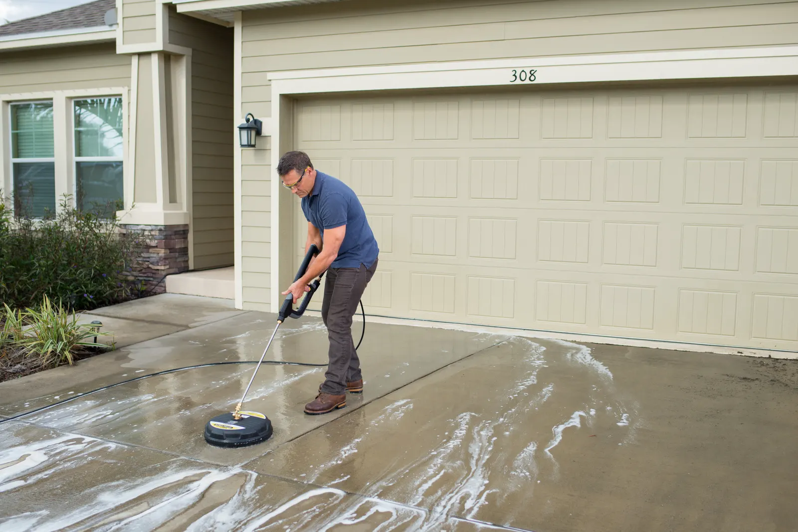 Surface cleaner lifting grime from a concrete driveway, half cleaned