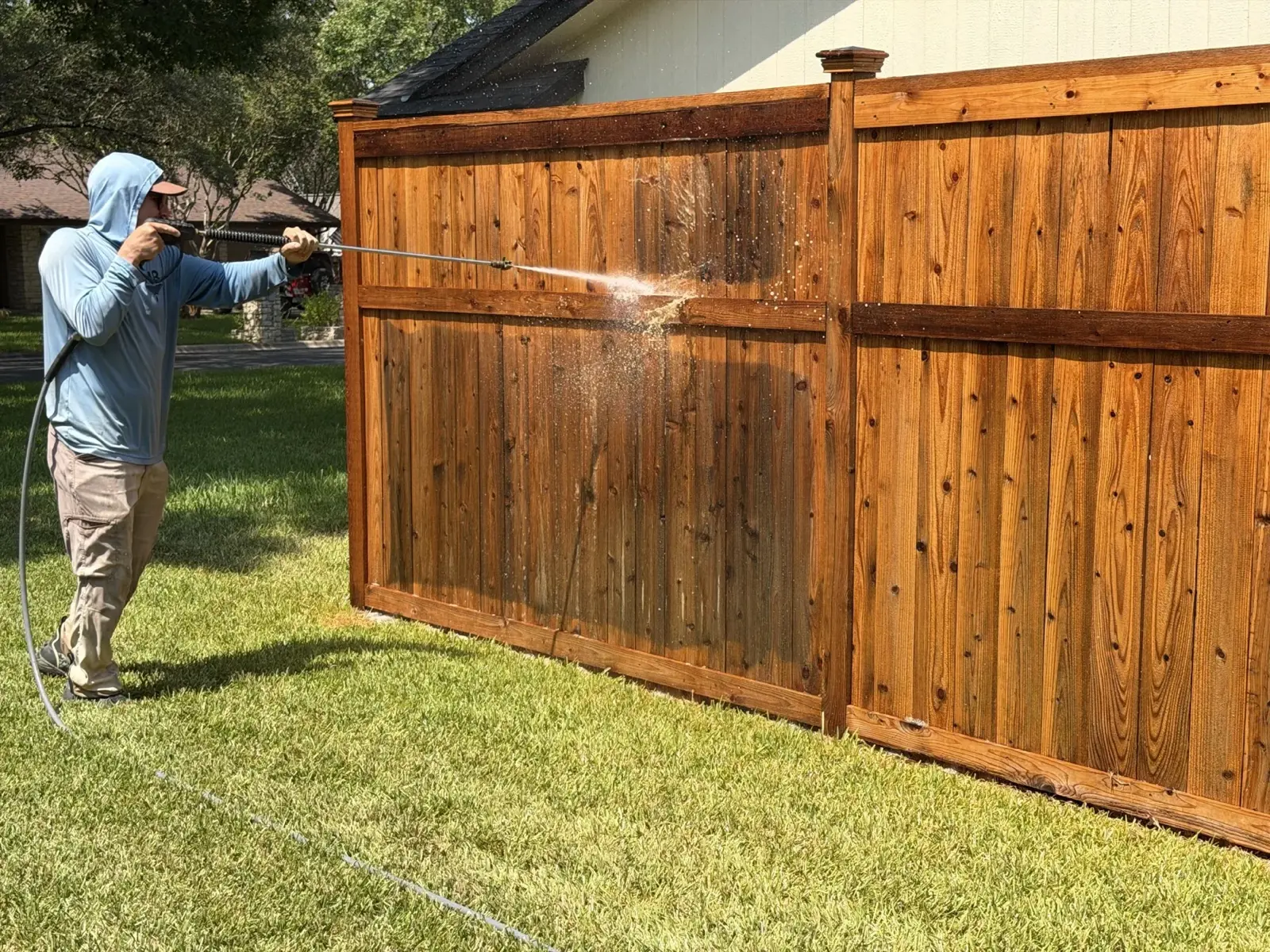 Wood privacy fence being pressure washed in a San Antonio area backyard