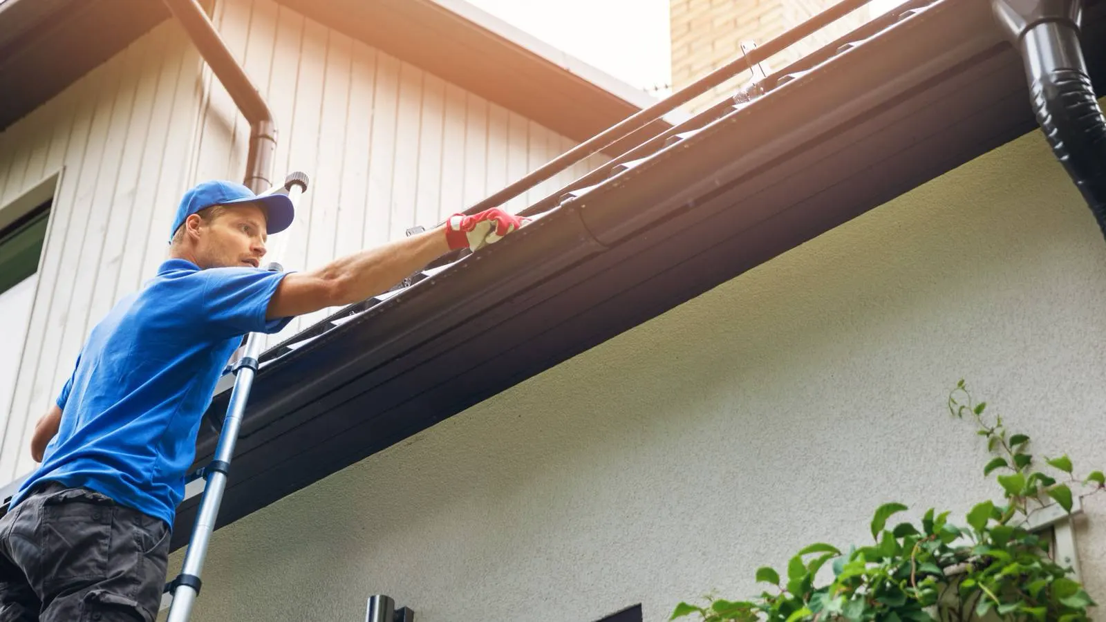 Technician on a ladder clearing debris from a home's gutters