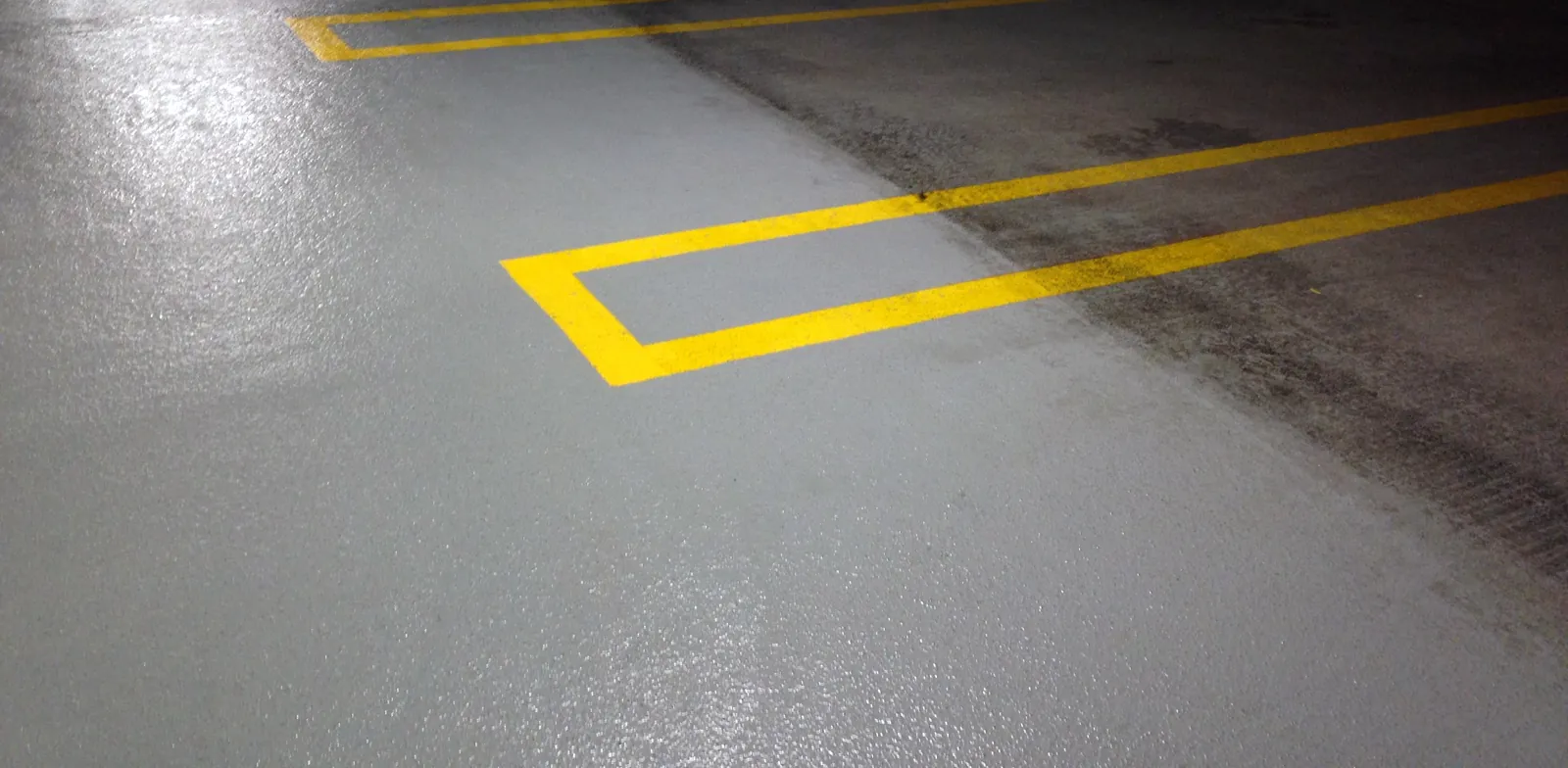 Parking stall concrete half pressure washed, the clean side beside built up grime