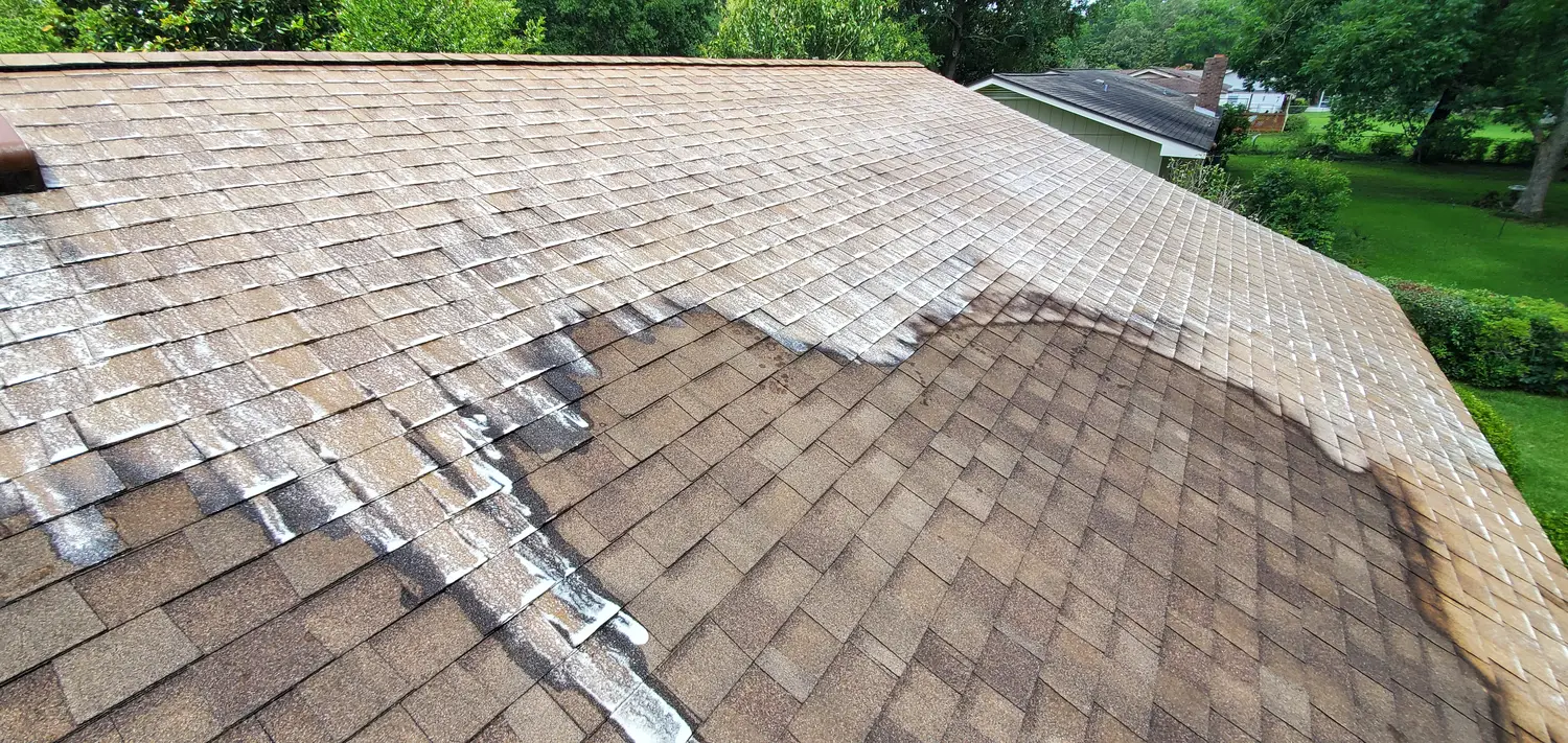 Soft wash solution foaming across a shingle roof mid clean