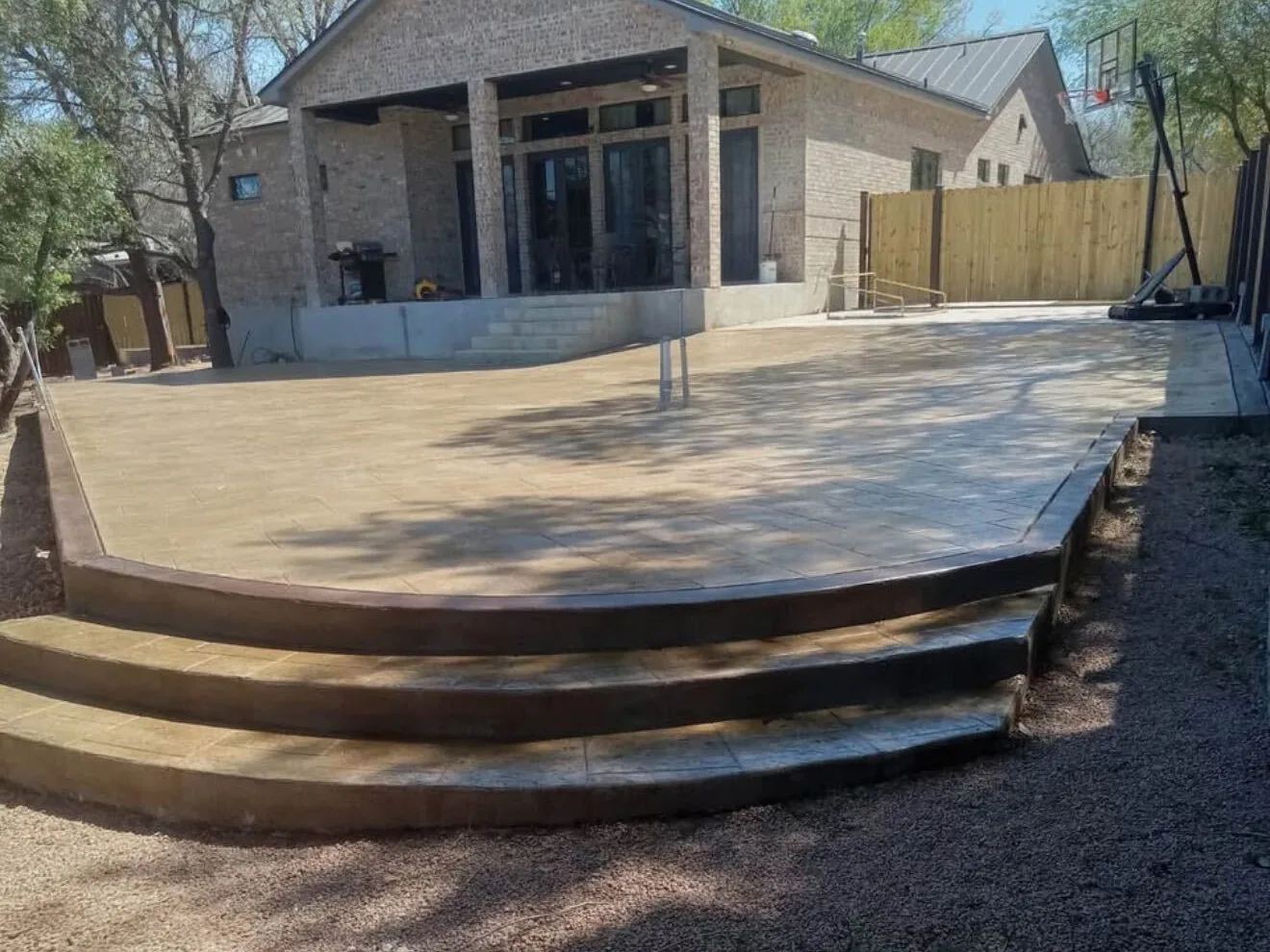Stamped concrete patio with a dark border and curved steps down to the yard