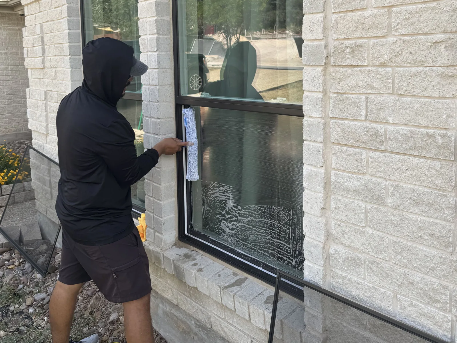 Window glass being scrubbed with a soapy applicator on a limestone home