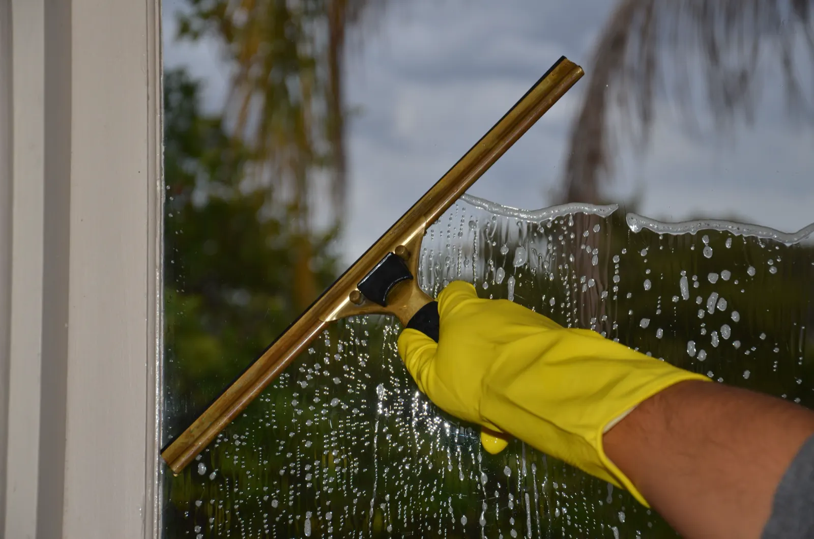 Squeegee pulling suds off a home's window glass